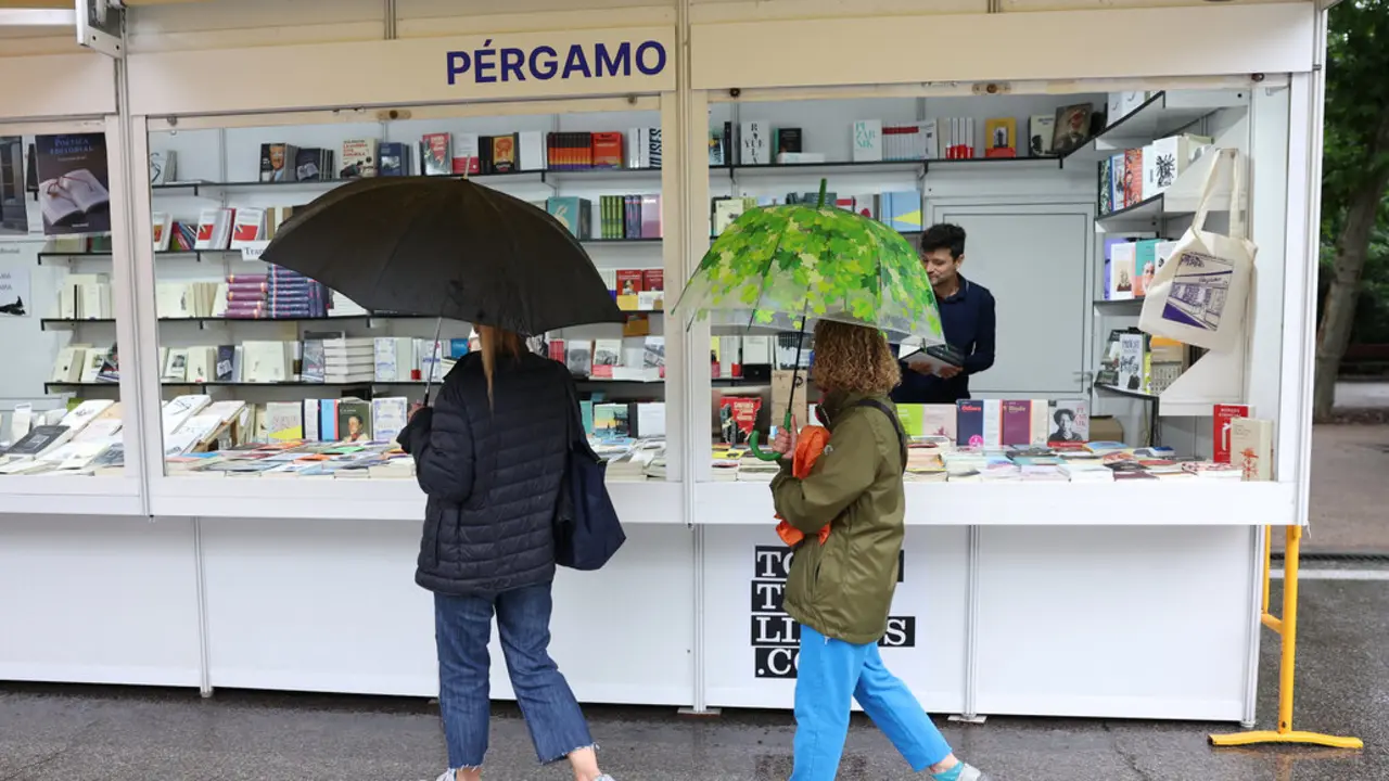 Visitantes bajo la lluvia en la caseta de la librer&iacute;a P&eacute;rgamo en la 82&ordf; #FLMadrid23 en el Retiro. 7 de junio de 2023. &copy; Isabel Infantes. Cedida por la Feria del Libro de Madrid.